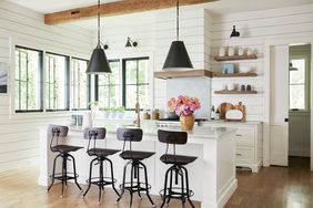 Pendant light hanging over kitchen island with chairs