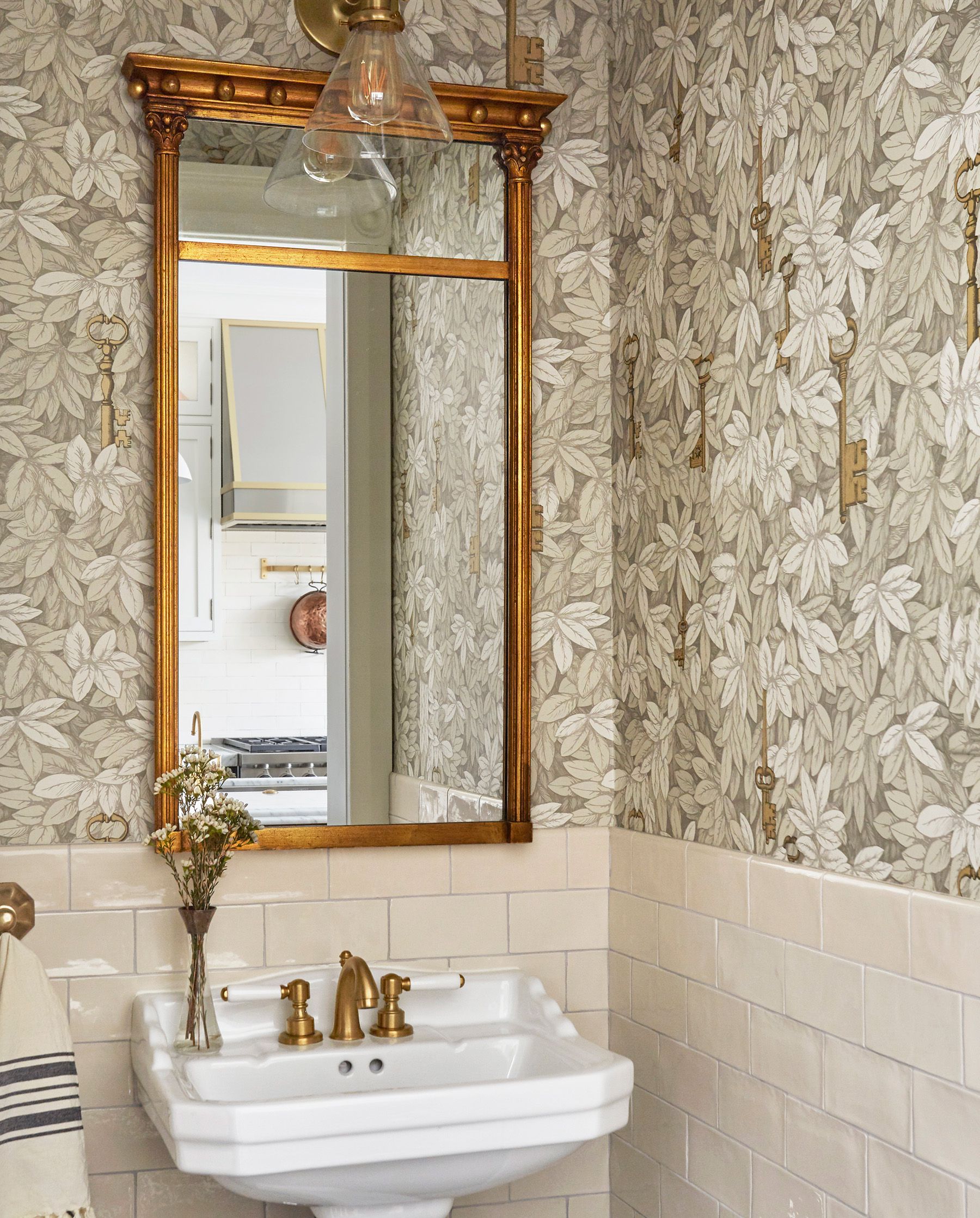 neutral floral wallpaper in bathroom with gold mirror