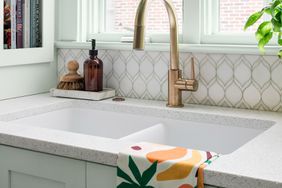 kitchen sink with brass faucet and colorful dish towel