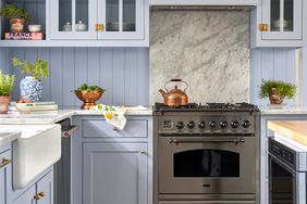 cottage style kitchen with light blue cabinets, butcher block island, carrera marble countertops and paneled backsplash