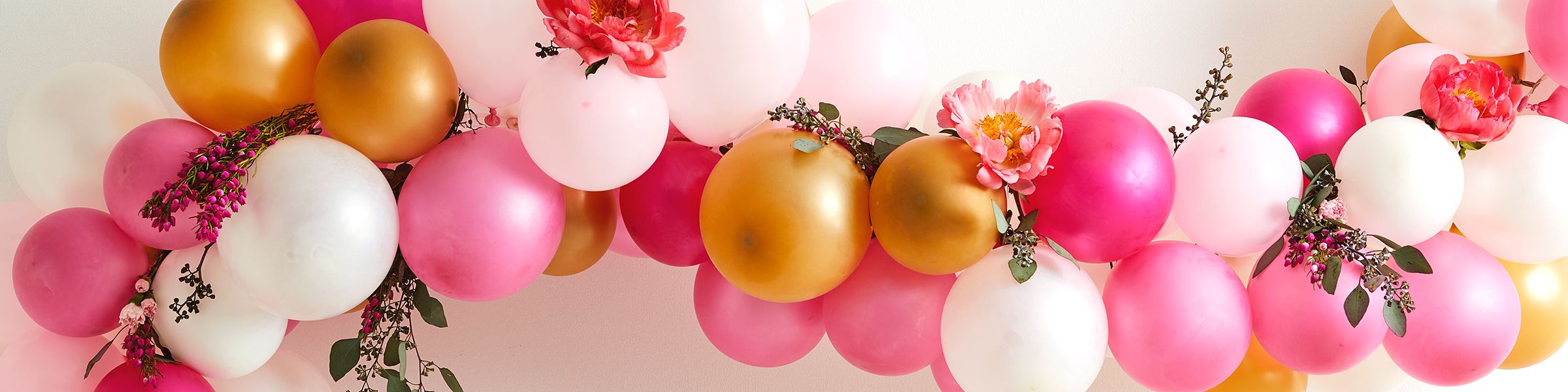 Pink and gold balloon garland hung on a wall