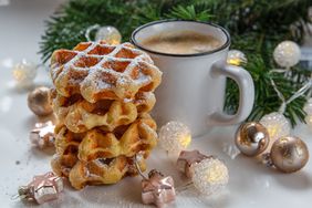 Mini waffles and cup of coffee with Christmas tree in background with ornaments