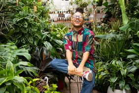 Christopher Griffin aka Plant Kween sits in a room full of houseplants