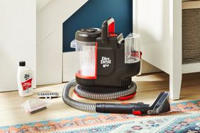 Dirt Devil Portable Spot Cleaner FD13000 displayed with its attachments in a living room next to a colorful patterned rug