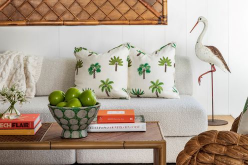Boucle couch with palm tree pillows, wooden coffee table, chic books