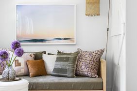 White room with gray daybed and pastel artwork