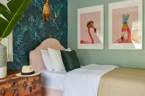 a jungle-themed kids room with pink flamingo art, a jute rug, and palm leaf wallpaper
