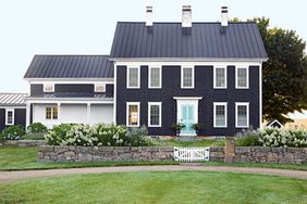 black farmhouse exterior with teal door and white trim windows