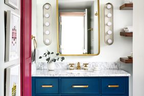 blue bathroom vanity with marble countertop and gold mirror