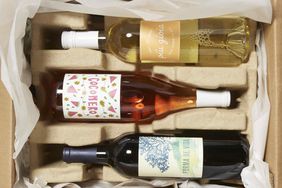 Carboard shipping box filled with a bottle of white wine, rose wine, and red wine