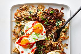a tray with rice and beef topped with sunny-side-up eggs