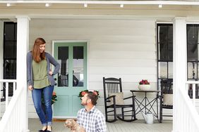 couple with dog on white front porch with green front door