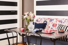 dining nook with black and white stripes on wall and floral cushion