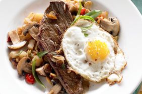 Frizzled Eggs over Garlic Steak and Mushroom Hash in white bowl