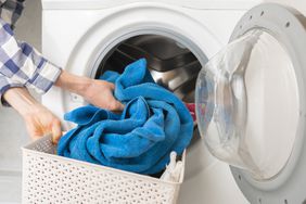hands putting towels into washing machine