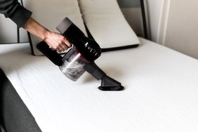 hand vacuuming mattress in bedroom
