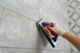 regrouting tile with grout brush on gray tiles