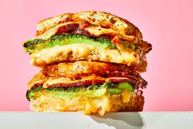 a toasted breakfast sandwich cut in half to show juicy oozy insides