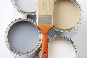 four open paint cans with paintbrush on top
