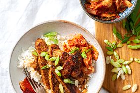 bowl of Spicy Tempeh Bulgogi with side of kimchi and green onions on cutting board