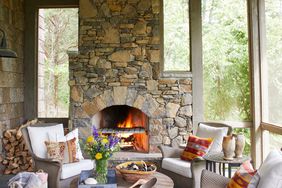 A screened-in porch with a stone fireplace and chairs