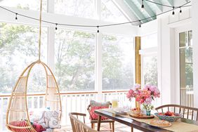 table with flowers by hanging chair on porch