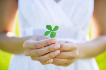 woman in white dress holding four leaf clover